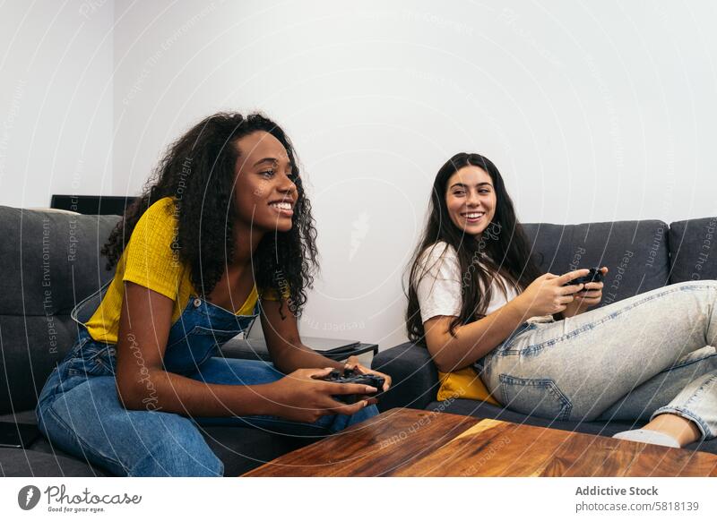 Friends bonding over console gaming in living room Women Console gaming Living room Fun Cozy Bonding Entertainment Video games Leisure Relaxation Joyful