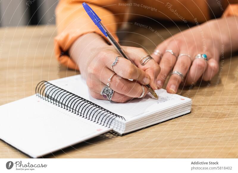 Crop woman taking notes in notebook during work in cafe freelance take note write project female planner netbook job distance table startup glad pen memo sit