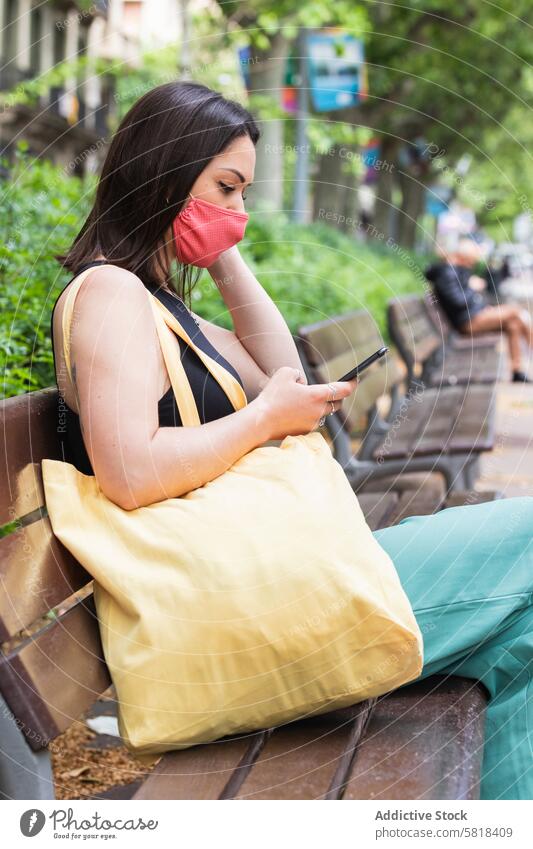 Woman in mask using smartphone in city during coronavirus woman new normal street browsing covid 19 female protect pandemic covid19 online gadget device mobile