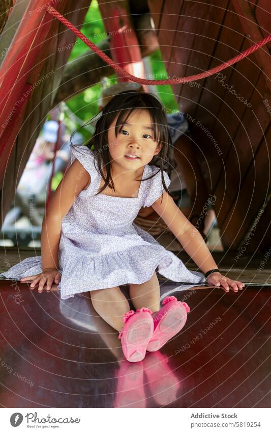Asian girl playing on a slide during family vacation asian child europe joy childhood travel adventure leisure activity outdoor fun happy playful cute park