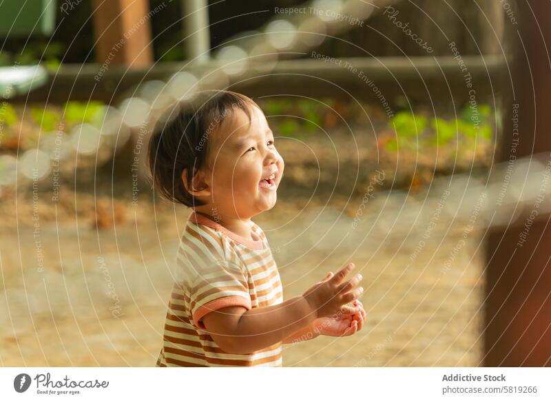 Asian Toddler Laughing Outdoors on Family Trip in Europe asian toddler child laughing outdoors vacation europe park joy innocence travel family summer happiness