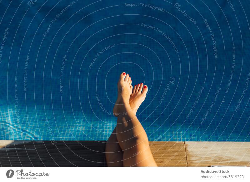 Relaxing feet over a swimming pool on a sunny day foot water blue relaxation summer vacation leisure female barefoot pedicure red nail polish tranquility rest