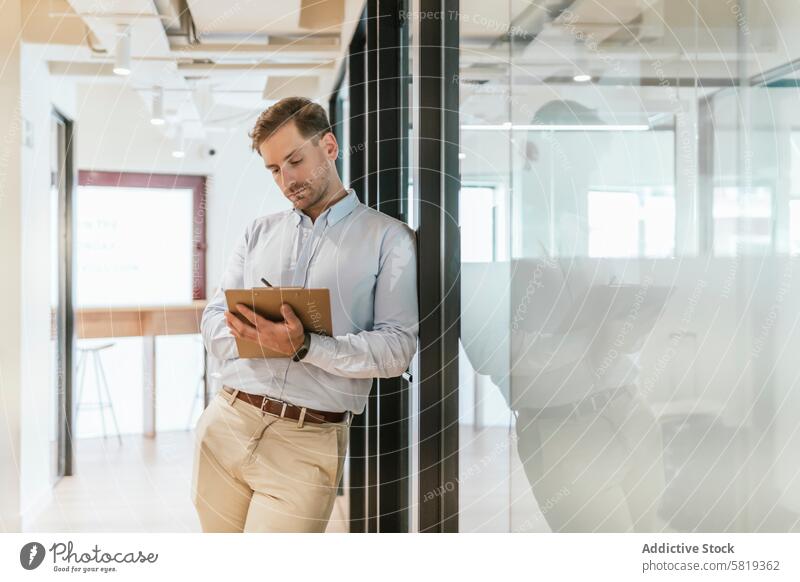 Professional man working in a modern coworking space professional office interior bright focused clipboard notes diligence contemporary environment business