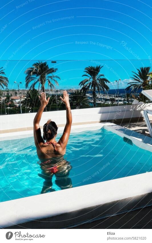 Woman with raised arms in the pool on summer vacation Summer bathe sea view palms Summer vacation Bikini tanned Lifestyle Water Swimming & Bathing Blue