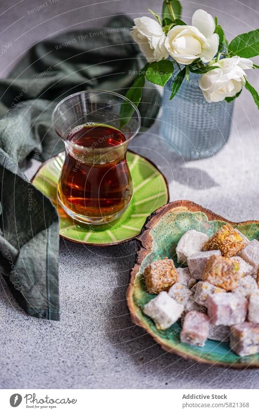 Turkish Delights and Black Tea with White Roses Decor turkish delight black tea glass white rose vase ceramic plate assorted traditional sweet confectionery