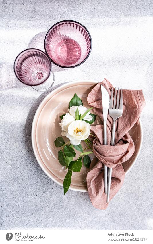 Elegant place setting with white rose centerpiece table plate napkin cutlery silverware fork knife elegance dining decoration floral flower terracotta texture