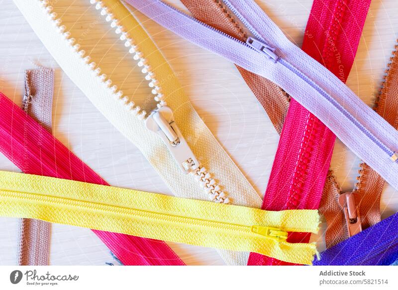 Colorful zippers on a wooden surface for craft projects sewing design textile colorful bright array variety workshop texture red yellow white purple brown teeth