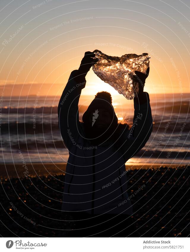 Holding a chunk of glacial ice in Icelandic sunset person silhouette iceland beach ice chunk sunrise outdoor nature travel adventure winter cold sunlight arctic
