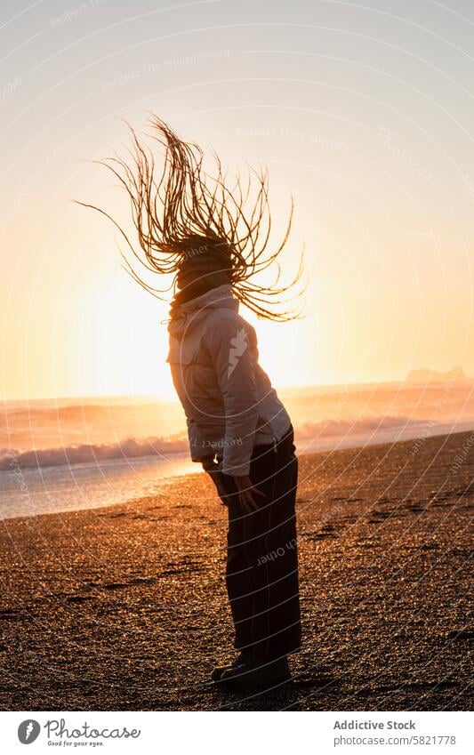 Whimsical silhouette of woman with flowing hair at sunset beach iceland golden dusk horizon sea wind blowing nature beauty freedom carefree wild glow bright