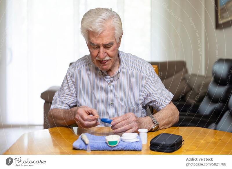Elderly man checking blood sugar levels at home elderly senior diabetes glucose meter health medical care table sit vigilance hypoglycemia testing monitor