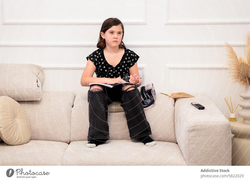 Young girl reading on sofa with thoughtful expression home book pensive casual look away preteen living room comfortable indoors child education study literacy