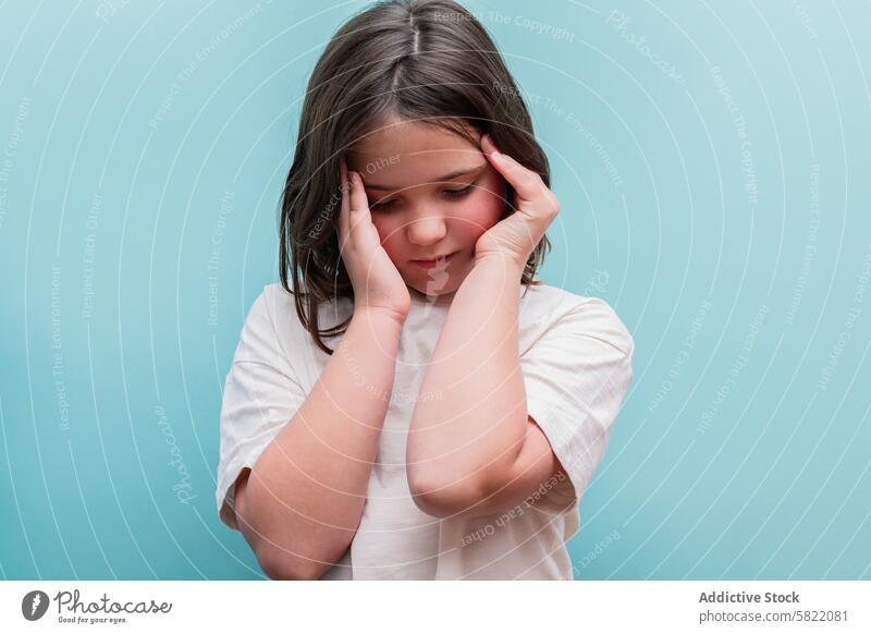 Young girl feels uneasy, possible hypoglycemia symptoms distress headache health illness child discomfort pain suffering blue background upset medical