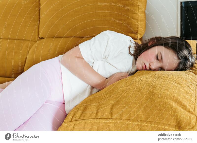 Woman resting on yellow sofa: indication of hypoglycemia woman couch fatigue indoor domestic health medical casual tired sleepy illness home physical discomfort