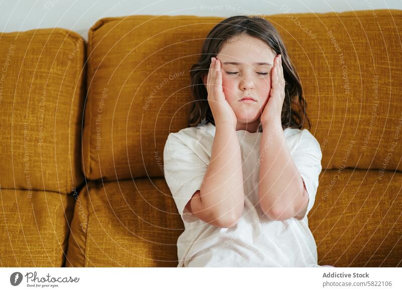 Young girl feeling unwell on couch, depicting hypoglycemia symptom hand face calm environment health illness medical discomfort child patient sugar glucose
