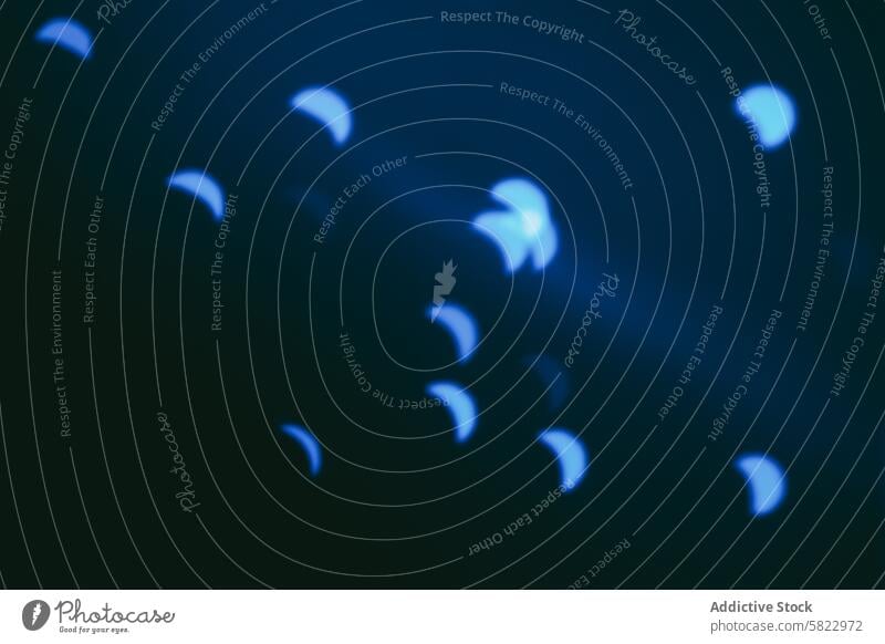 Abstract blue shapes resembling crescent moons on dark background abstract mysterious dreamlike atmosphere blur soft focus bokeh light pattern scattered design