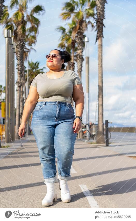 Casual stroll on a sunny day in Barcelona woman walk summer barcelona palm tree casual confidence urban lifestyle leisure street fashion denim jeans t-shirt