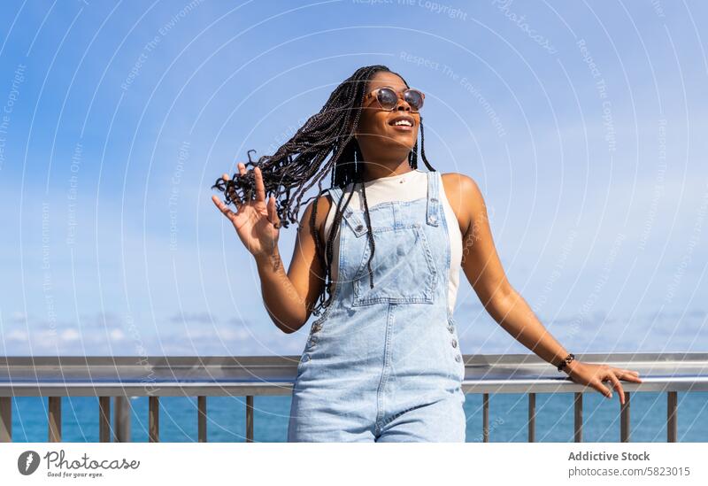 Joyful summer day with friends in Barcelona woman barcelona sea happy young sunglasses denim overalls smile joy casual fashion hairstyle african american braid