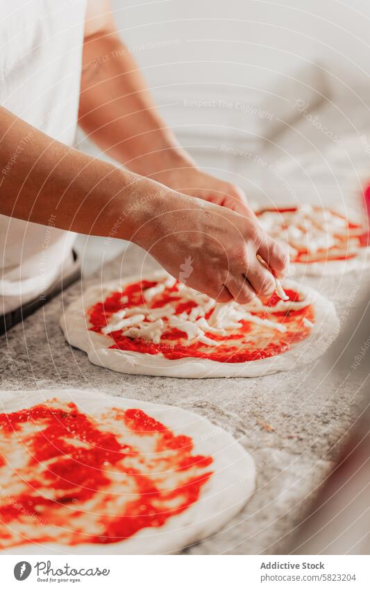 Preparing pizza in a professional kitchen setting chef anonymous pizzeria preparation sauce cheese dough cooking hand topping food baking cuisine italian meal