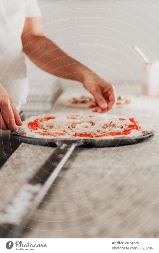 Preparing classic pizza in a professional kitchen pizzeria chef preparation cooking topping tomato sauce onion peel dough food gourmet italian cuisine meal