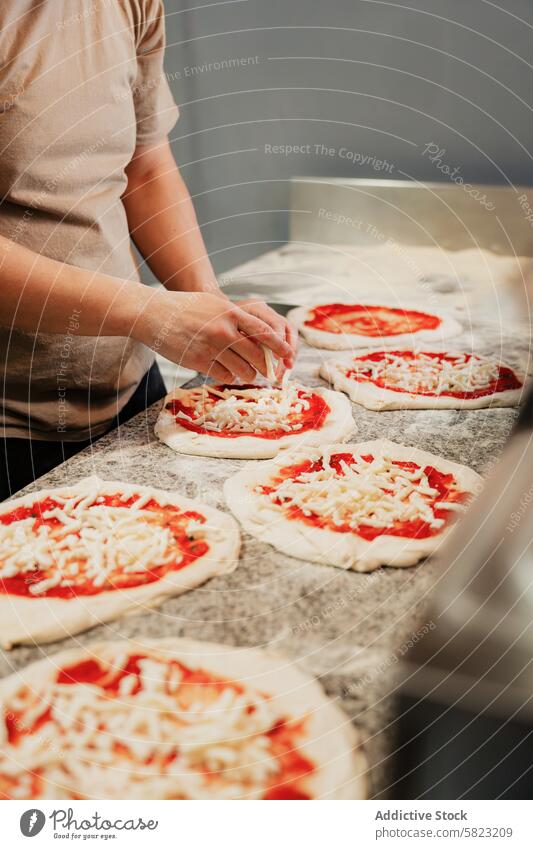 Preparing handmade pizzas in a pizzeria kitchen preparation chef dough sauce cheese cooking anonymous faceless cropped food meal cuisine italian baking