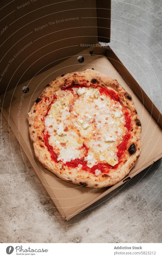 Fresh pizza in a box on a concrete surface takeaway delivery pizzeria food meal cheese tomato dough baked crust cardboard overhead view fresh hot lunch dinner