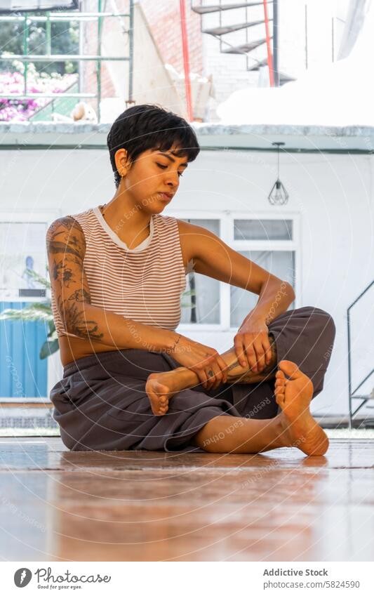 Woman preparing for holistic dance ceremony woman stretching serene tattoo preparation seated foot bright space individual wellness health meditation balance