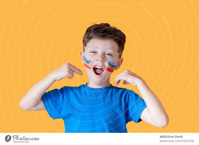 Young boy with face paint young child cheerful happy fan supporter sport team game pride colorful cheek point gesture celebration enthusiasm joy smiling
