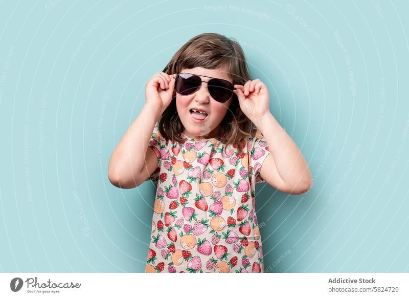 Young girl smiling and adjusting her sunglasses a Royalty Free Stock Photo from Photocase