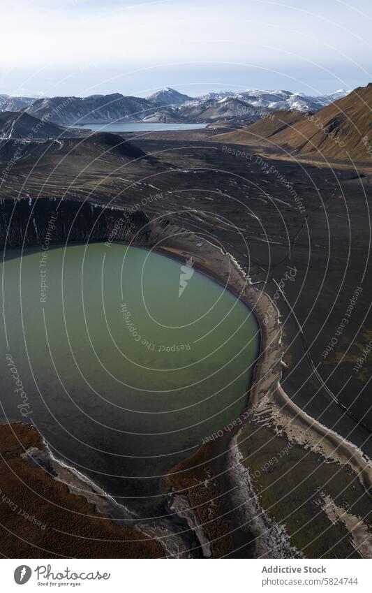 Aerial view of a crater lake in the highlands aerial landscape serene beauty shot capture nestled rugged undulating hill distant snow-capped peak volcanic