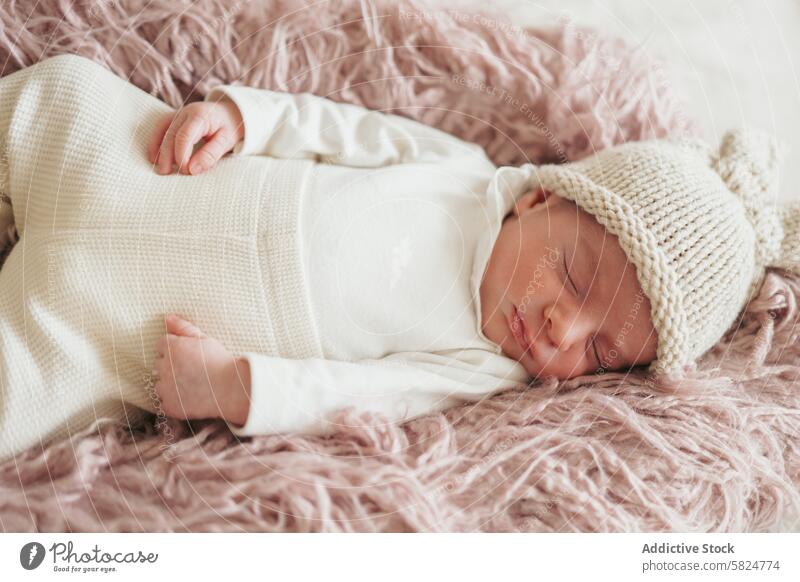 Peaceful newborn sleeping on soft pink blanket baby peaceful serene infant child cozy white knitted hat nap rest calm restful quiet comfortable cute adorable