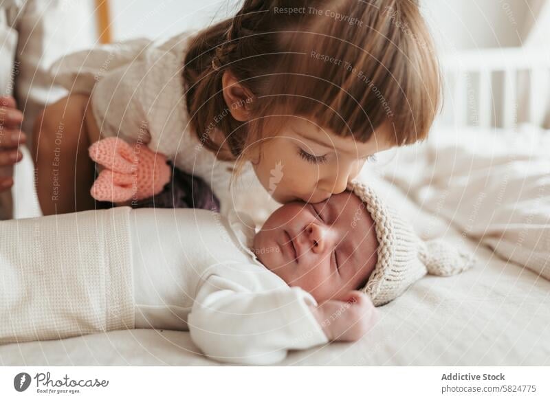 Toddler sister giving a gentle kiss to her sleeping newborn brother toddler baby affection love tenderness moments family siblings care child bonding innocence