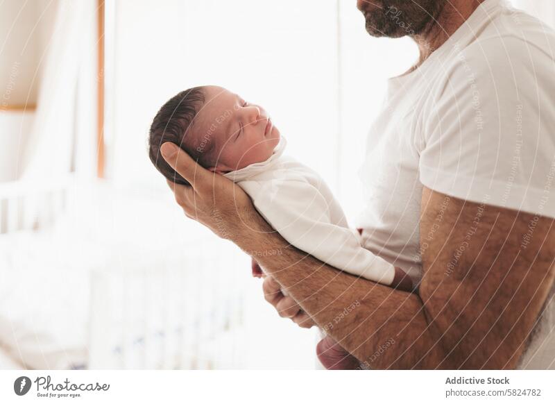 Tender father-baby embrace in soft white clothing newborn cradle gentle paternal bond family care love tenderness affection child parenthood dad infant holding
