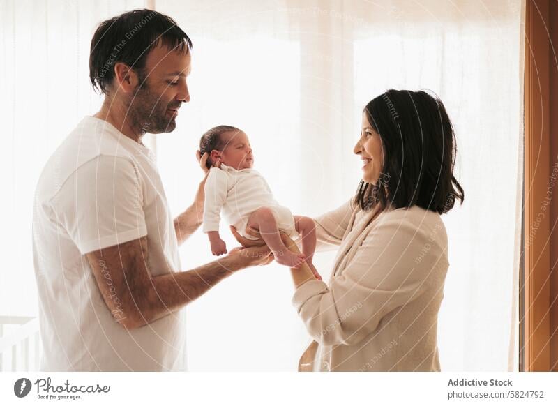 Tender moment with new parents and their baby family newborn mother father love tender child infant holding smile joy happiness home indoor room soft light care
