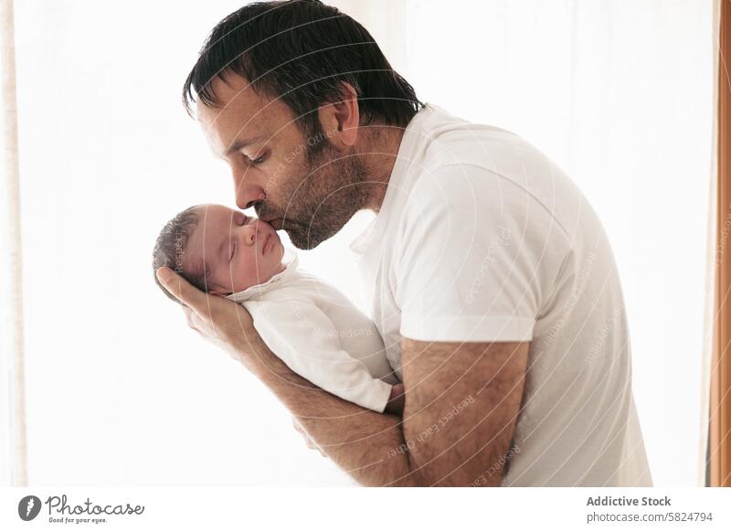 Tender moment between father and newborn baby kiss embrace love affection tender parent child family peaceful caring bond fatherhood man infant sleep care white