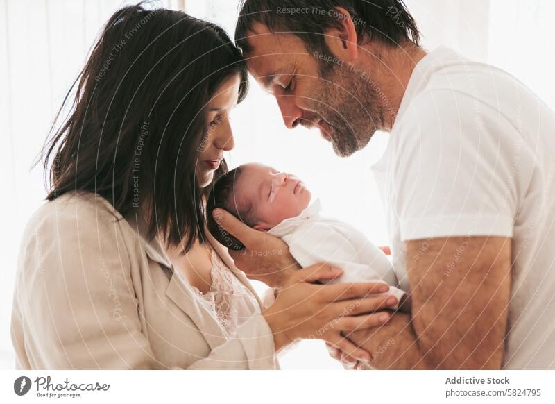 New parents adoring their sleeping newborn baby family mother father love affection tender care bond cradle child infant life beginning parenthood nurturing