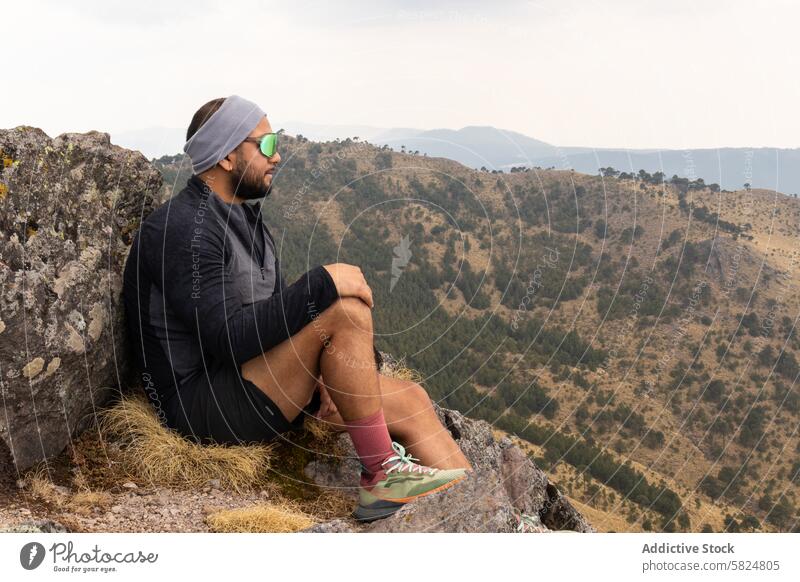 Hiker reflecting on mountaintop during training session hiker trail resting contemplation scenic man pause gaze outdoor adventure sport exercise fitness nature