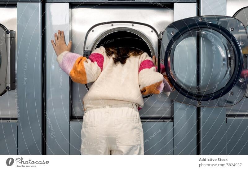 Preteen girl looking inside the washing machine preteen laundry curious searching leaning looking away child laundry room clothing chores domestic washer door