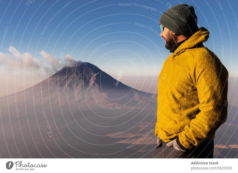 Hiker overlooking Iztaccihuatl Volcano at dawn hiker iztaccihuatl volcano sunrise adventure outdoor mountain peak yellow jacket nature landscape exploration