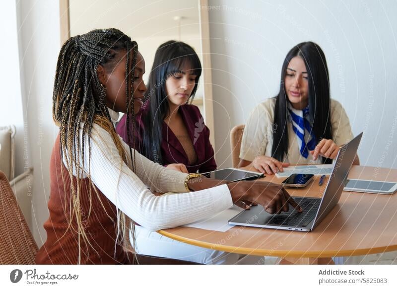 Three diverse women collaborating on a project at home woman work laptop collaboration office diversity teamwork technology communication professional business
