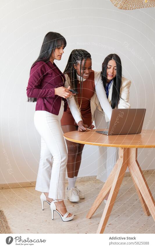 Three women collaborating on a project using a laptop at home woman work business collaborate multiethnic diverse desk setting indoor technology team teamwork