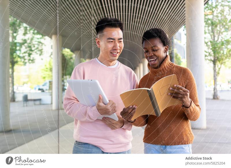 Multicultural students sharing ideas outdoors multicultural education discussion asian african tablet notebook campus cheerful friends conversation university