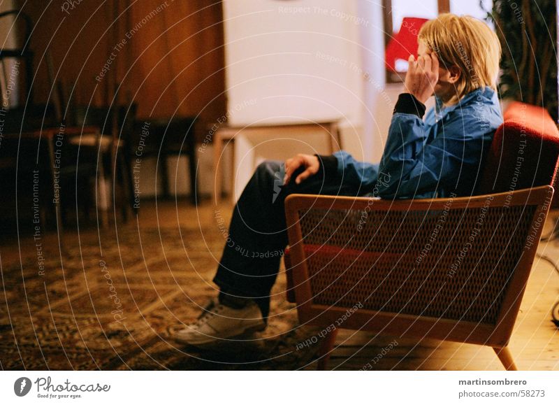 Thinking in the sofa Cozy Carpet Sofa Red Young woman Pants Sneakers Blonde Cool-headed Interior shot not light not dark Old wooden backrest blue jacket Sit