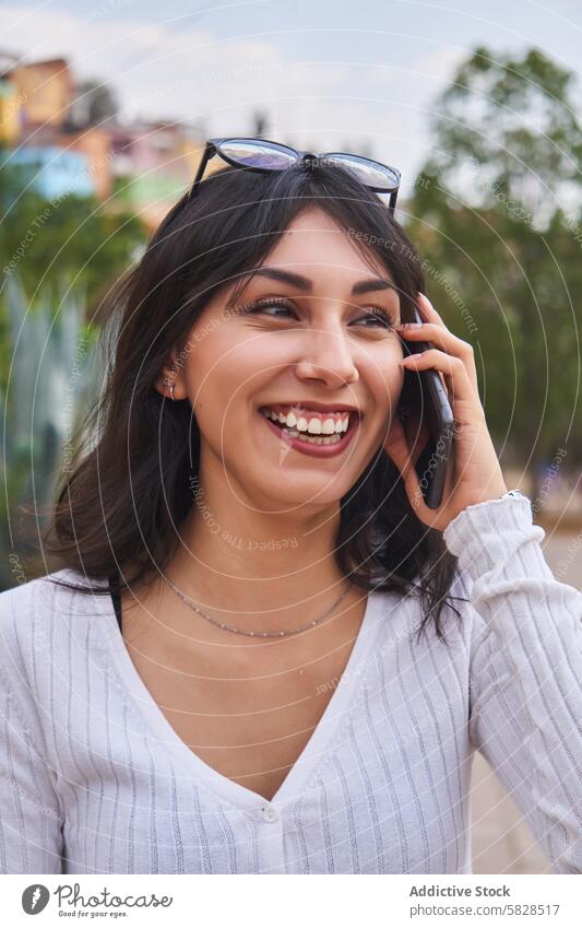 Smiling woman enjoying phone conversation outdoors smiling mobile park laughter connectivity happiness communication technology cellphone smartphone nature