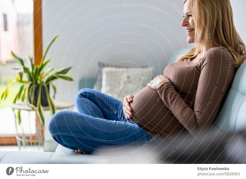 Pregnant woman touching her belly, relaxing on sofa at home pregnancy pregnant adult anticipation awaiting baby birth body care caucasian child expectant