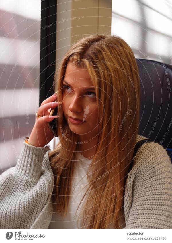 A young woman talks on her cell phone on a train Cell phones Color photo mobile phone dead Telecommunications PUBLIC TRANSPORT Track Public transit