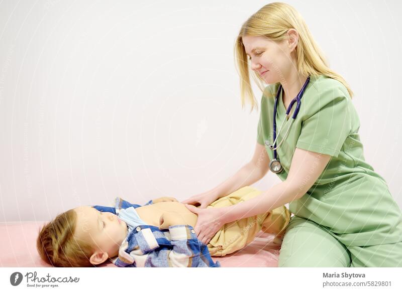 Cute toddler boy is at an appointment with pediatrician. Doctor gastroenterologist palpating belly of little child patient lying on couch in medical office. Gastroenterological diseases of kids