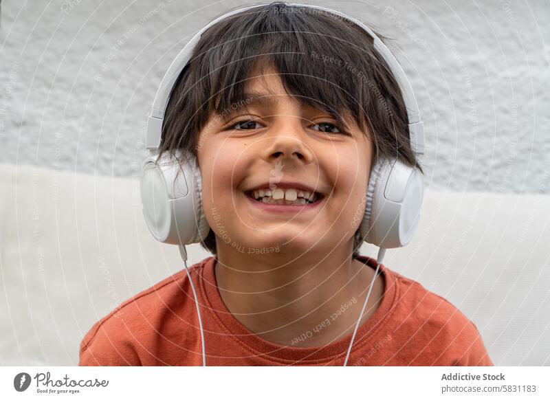 Joyful boy enjoying music with headphones in spring smiling weekend grandpa leisure casual wear child happy entertainment technology audio young listen white