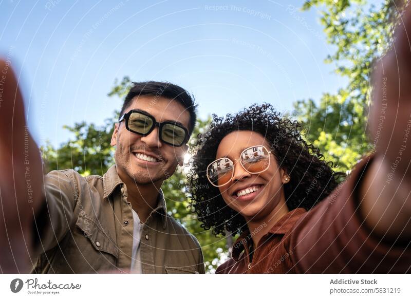 Multiethnic couple enjoying sunny day in Madrid park together diversity love relationship outdoors smiling happy sunglasses greenery sky environment nature
