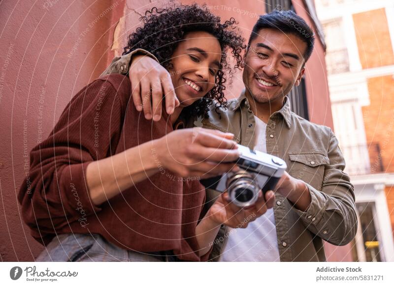 Multiethnic couple exploring Madrid and reviewing camera photos multiethnic chinese hispanic madrid spain photography travel city urban tourism fun smile happy