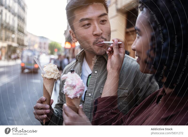 Multiethnic couple enjoying ice cream in Madrid city street man woman chinese hispanic madrid spain sunny day urban romance love relationship diversity